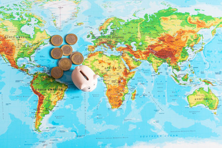 A tiny piggy bank is standing on a colorful map of the world, next to money. Travel concept.