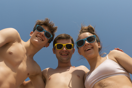 Happy family. Dad and two teenage children in colorful sunglasses laugh. Wide Angle.の写真素材