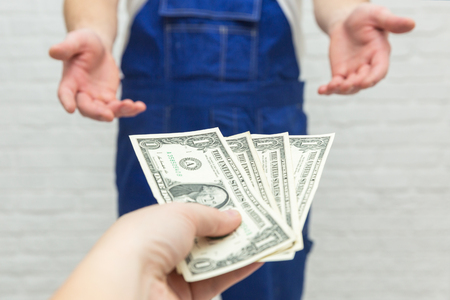 The client will pay the contractor for the work performed. The feminine hand gives money to the men's hands. Finance concept.の写真素材