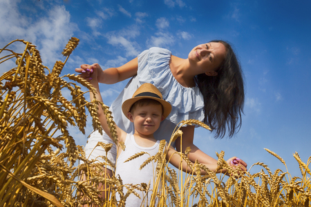 Happy family. Mom and son are laughing and talking on the wheat field. Front view.の写真素材