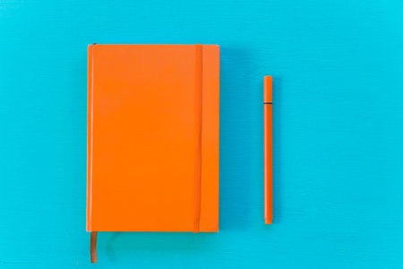 Orange note and pen on blue background