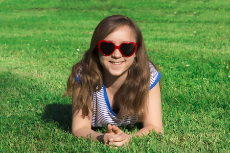 Happy smile beautiful and young girl spanding time in city park. Red hearts sunglasses.の写真素材