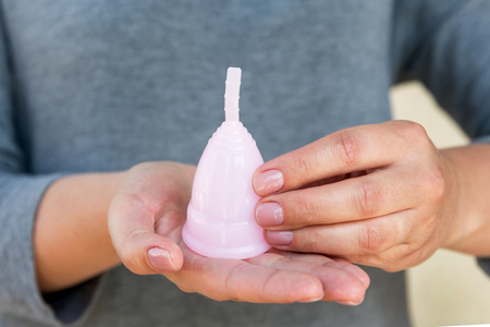 The menstrual cup is holding by woman hands. Selective focus.の写真素材