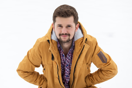 A young beautiful man with dark hair with a beard is pleased with the first snow. Winter time.の写真素材