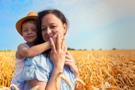 Happy family. Mom and son are laughing and talking on the wheat field. Front view.の写真素材