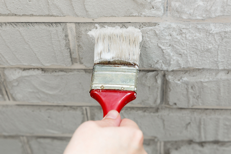 ladies hand painted brick brush white wall. Renovation work. White background.の写真素材