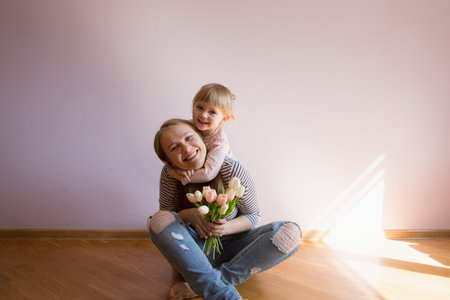 Happy family. Daughter gives a bouquet of flowers (tulips) to her mother in the room. Naturally...