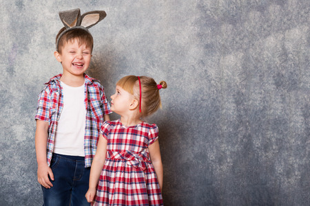 Two children, a girl and boy with Easter rabbit ears on head laugh and play. Family Easter. Copy space.の写真素材