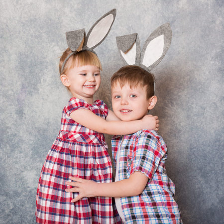 Two children, a girl and boy with Easter rabbit ears on head laugh and play. Family Easter. Copy space.の写真素材