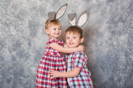 Two children, a girl and boy with Easter rabbit ears on head laugh and play. Family Easter. Copy space.の写真素材