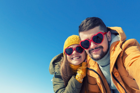 Happy couple making selfie on a winter sunny day. Wide angle, copy space, toned.の写真素材