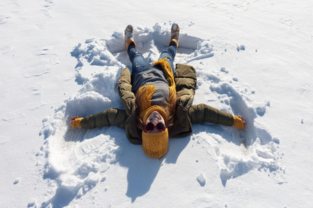 The girl is making an angel in the snow.の写真素材