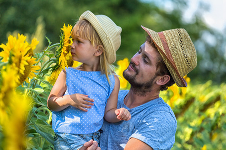 Father and daughter are smelling sunflowerの写真素材