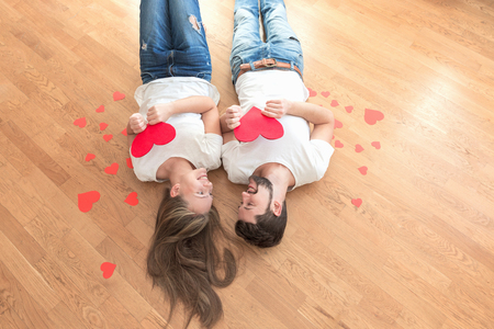 Top view of happy young couple with paper hearts. They look at each other.の写真素材