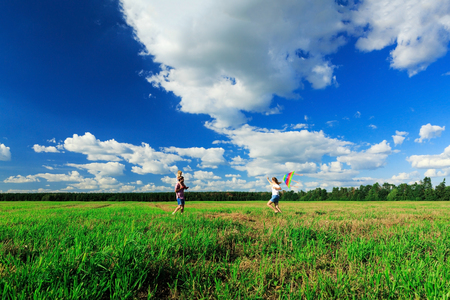 Happy family. Mother, father and daughter are flying a kite in the field.の写真素材