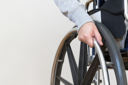 Detail of disabled woman holding a hand on wheel of a wheelchair. Close up.の写真素材
