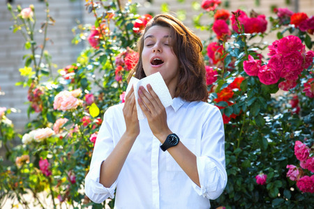 Young girl blowing nose in garden. Spring allergy concept.の写真素材