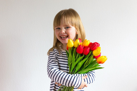 Happy mothers day! Cute little girl holds colorful flowers of tulips. Copy space.の写真素材