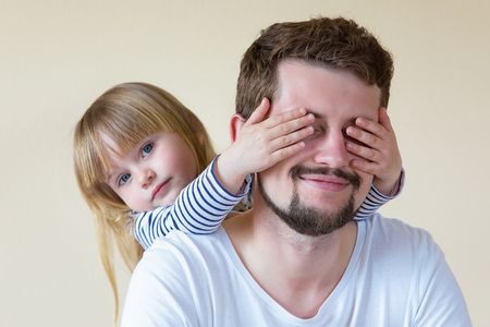 Cute little girl making surprise for her father.の写真素材