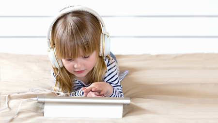 Focused little child using laptop with headphones studying  e-learning.の写真素材