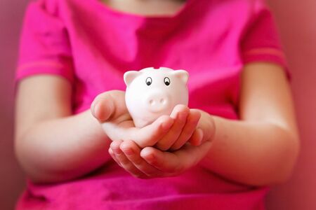 Pink piggy bank on children hands. Close up, selective focus.の写真素材