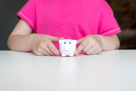 Children hands holding small piggy bank. Pink backgroundの写真素材