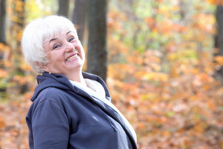 Portrait of beautiful senior woman in an autumn parkの写真素材