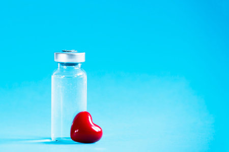 Medical ampoule with little red heart. Vaccination concept.