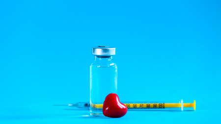 The vaccination glass bottle with a syringe and a little red heart. Vaccination with love concept.の写真素材