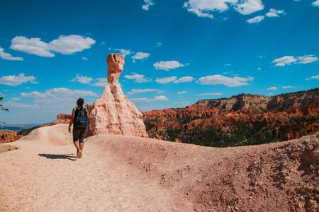Hiker woman in Bryce Canyon hiking looking and enjoying view during her hike wearing hikers backpack. Bryce Canyon National Park landscape, Utah, United States. Sunny Day, clear skies, hot summer.の写真素材