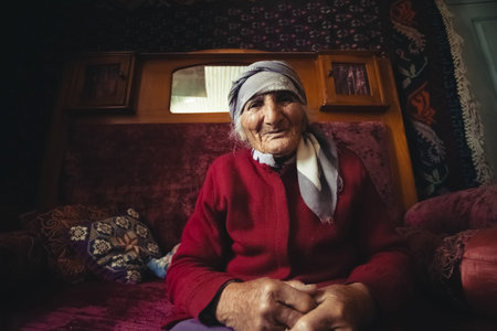Ushguli, Georgia - June 12, 2014: Elderly Georgian woman sitting at her house in the Caucasus Mountains villageのeditorial素材