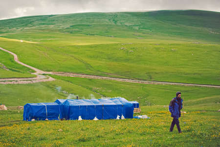 NEAR KAZBEGI, GEORGIA - June 12: Local shepherd in the green field, surrounding by mountain hills.のeditorial素材
