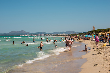 Tourists in Playa de Muro beach with Can Picafort town and mountains in background, northern part of Majorca islandのeditorial素材
