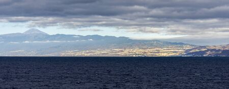 Distant panoramic view of Santa Cruz de Tenerife city with Mount Teide summit in the background, Canary Islands, Spainの写真素材