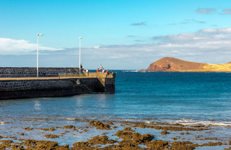 Local residents are fishing from a pier at El Medano town, Tenerife, Spain