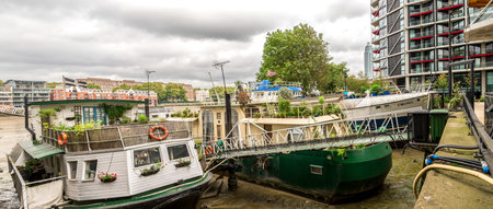 Boats parked near residential blocks and Nine Elm Elms tavern on southbank of river Thames near Battersea, Londonのeditorial素材