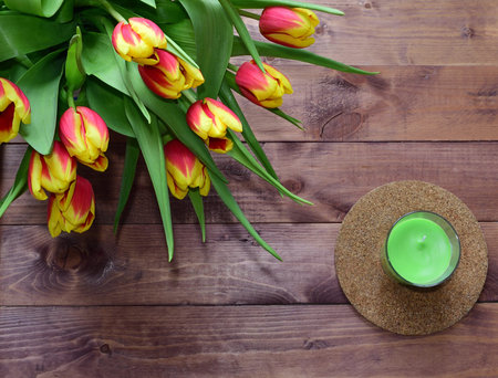 Spring Easter bouquet of tulip flowers with candle on wooden background.View with copy space
