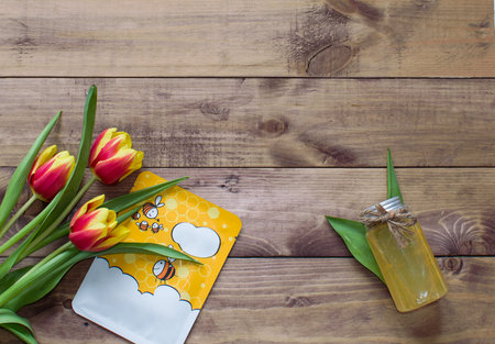 Flatlay Spring Easter bouquet of tulip flowers with cosmetic products, mask on wooden...