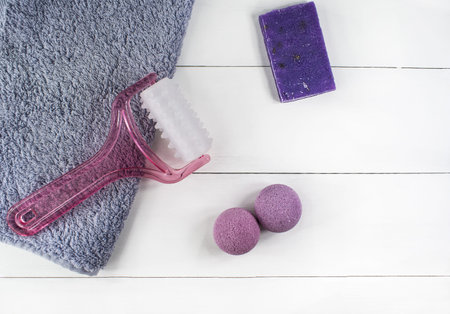 Flat lay spa bath on white wooden background, top view cosmetic products for face and body. Bombs, handmade soap lavender and massager with towel.の写真素材