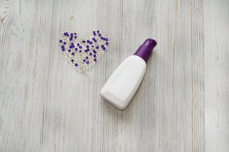 Cosmetic flat lay with hydrogel balls in the form of heart and bottle cream on grey wooden...