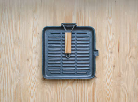 Cast iron grill pan on a wooden background. Black empty grill pan top view.の写真素材