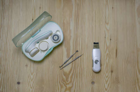 Cosmetic flat lay with electric and ultrasonic scrubbers, spoon and loop for cleansing face on wooden background.の写真素材