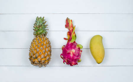 Exotic asia fruits on white wood background. Assorted tropical summer fruits. Mango, dragon fruit, pitahaya and pineapple. Top view fresh fruit flat lay.の写真素材