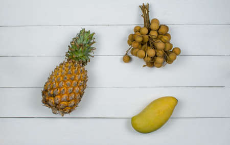 Exotic asia fruits on white wood background. Assorted tropical summer fruits. Mango, dragon eye, lychee, longan and pineapple. Top view fresh fruits flat lay.の写真素材