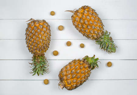 Exotic asia fruits on white wood background. Assorted tropical summer fruits. Dragon eye, lychee, longan and three pineapple. Top view fresh fruits flat lay.の写真素材