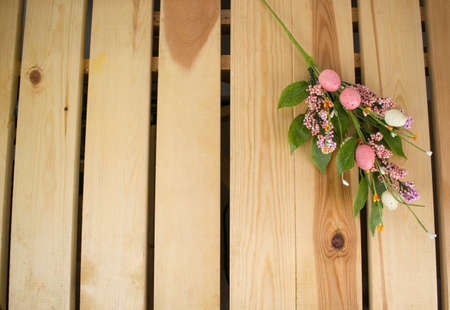 Easter wallpaper. Spring bouquet of flowers, colorful small eggs on light, yellow wood background. Flatlay house interior.の写真素材