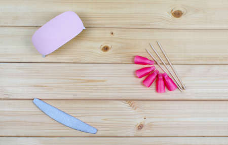 Pink plastic caps for nails. Flatly, top view beauty tools for manicure and pedicure. Nail polisher, bamboo sticks for cuticles. LED dryer mini lamp for gel.の写真素材