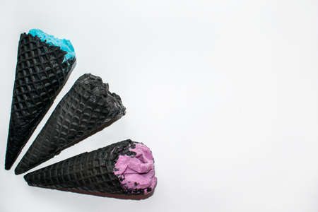 Colorful ice cream in black horns isolated on a white background. Top view three coal ice cream cones with dairy blue, violet and black balls.の写真素材