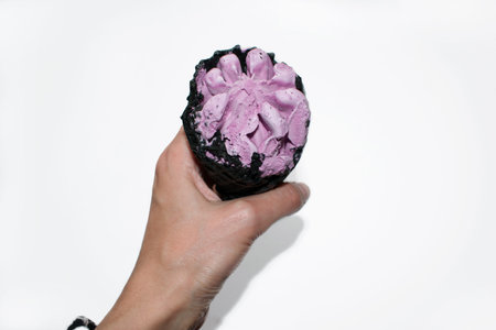 Pink ice cream in black horn in the women hand isolated on a white background. Top view maro coal ice cream cone with soft dairy violet ball.の写真素材