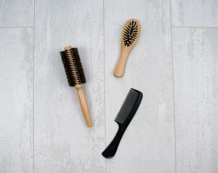 Close up of natural wooden hairbrushes. Massage, round with a bristle, plastic combs with handle isolated on a wood background.の写真素材